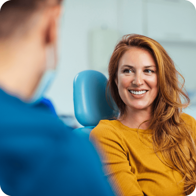 A female patient in a dental chair receiving treatment from a dentist.